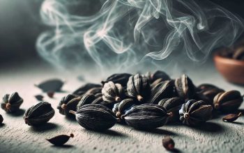 Close-up of smoky black cardamom pods with rising smoke on a wooden surface, showcasing their aromatic appeal.